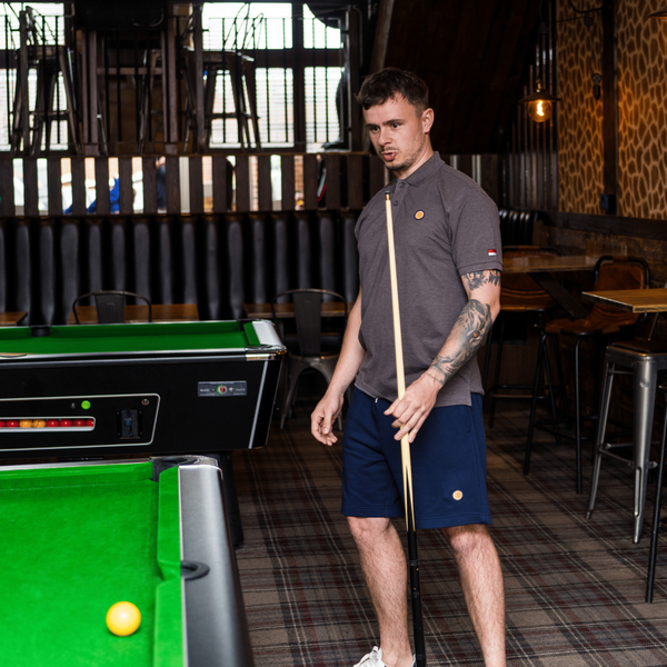 Man holding a pool cue standing next to a pool table in a bar setting