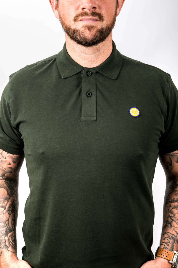Man wearing a green polo shirt with a small yellow logo on a white background