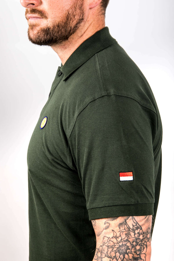Man wearing a green polo shirt with small flags on a plain background
