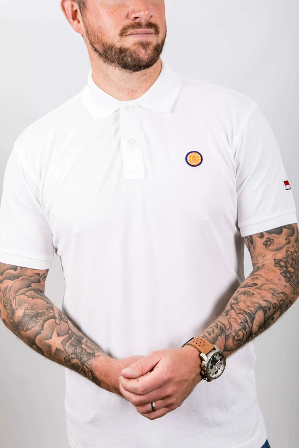 Man wearing a white t-shirt with a small logo on a plain background