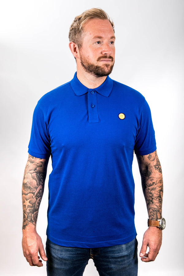 Man wearing a blue polo shirt with a small yellow logo on a white background
