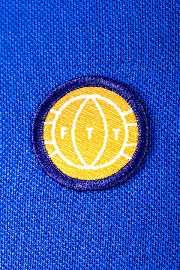Yellow and white logo patch with 'FTT' on a blue textured background