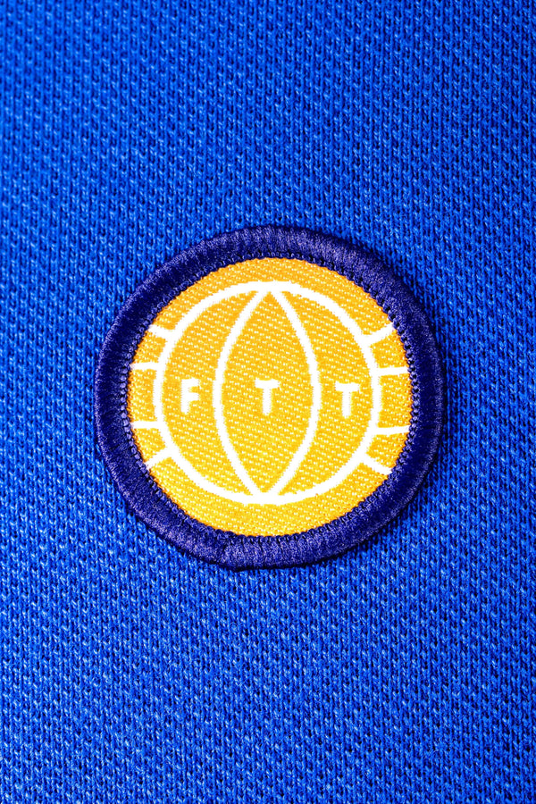 Yellow and white logo patch with 'FTT' on a blue textured background