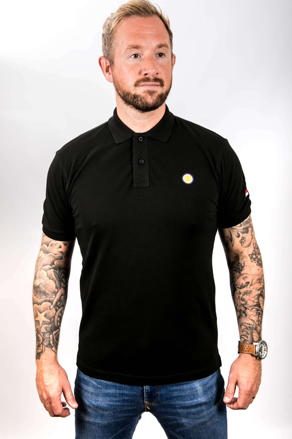 Man wearing a black polo shirt with a small yellow logo on a white background