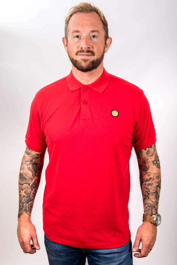 Man wearing a red polo shirt with a logo on a white background