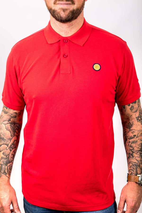 Person wearing a red polo shirt with a small logo on a white background