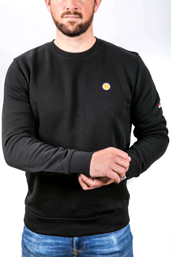 Person wearing a black sweatshirt with a small logo on a white background