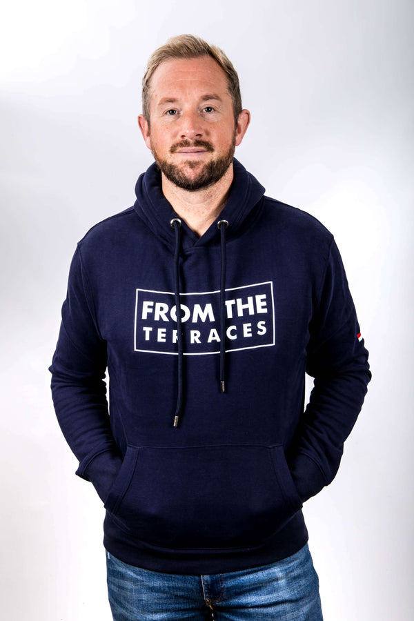 Man wearing a navy hoodie with 'From the terraces' text on a white background