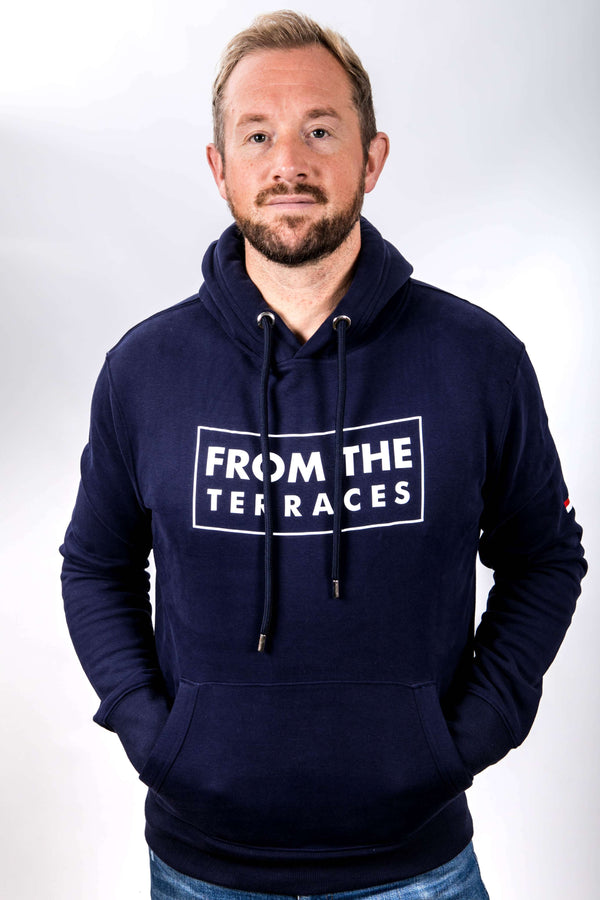 Man wearing a navy hoodie with 'From the Terraces' text on a white background