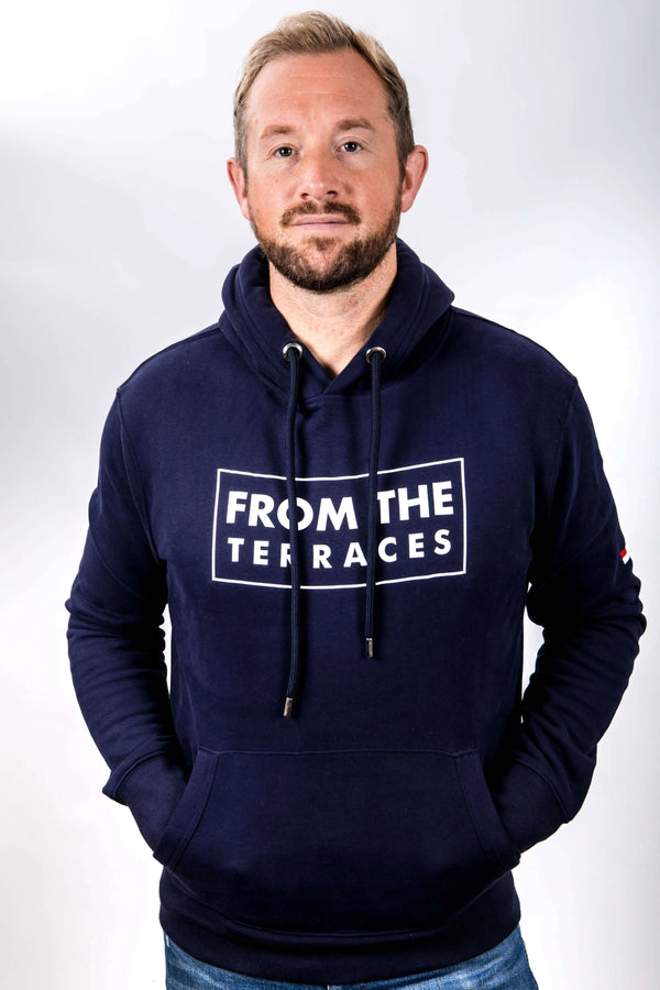 Man wearing a navy hoodie with 'From the Terraces' text on a white background