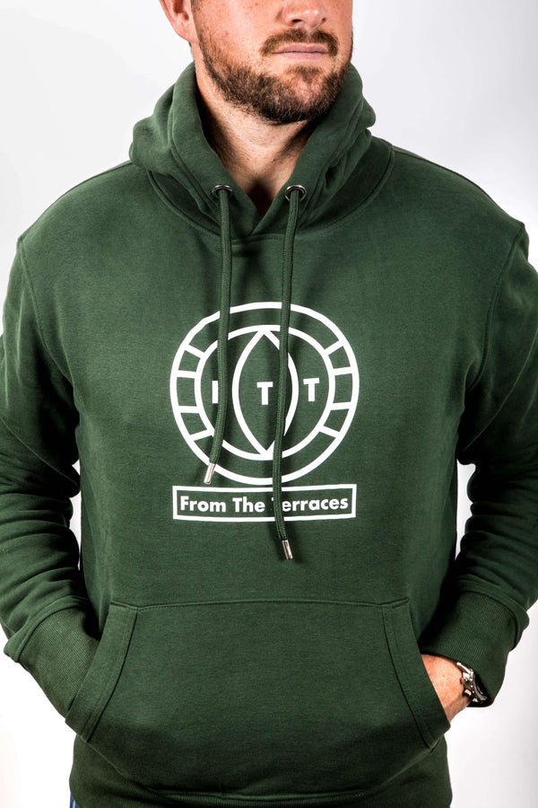 Man wearing a green hoodie with a logo and text on a white background