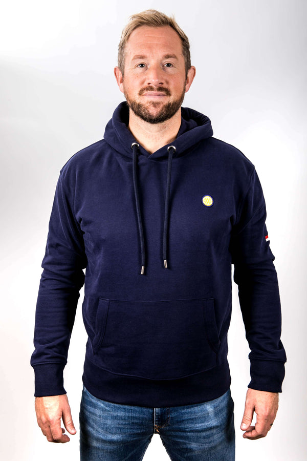 Man wearing a navy hoodie with a small logo on a white background