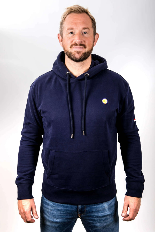 Man wearing a navy hoodie with a small logo on a white background