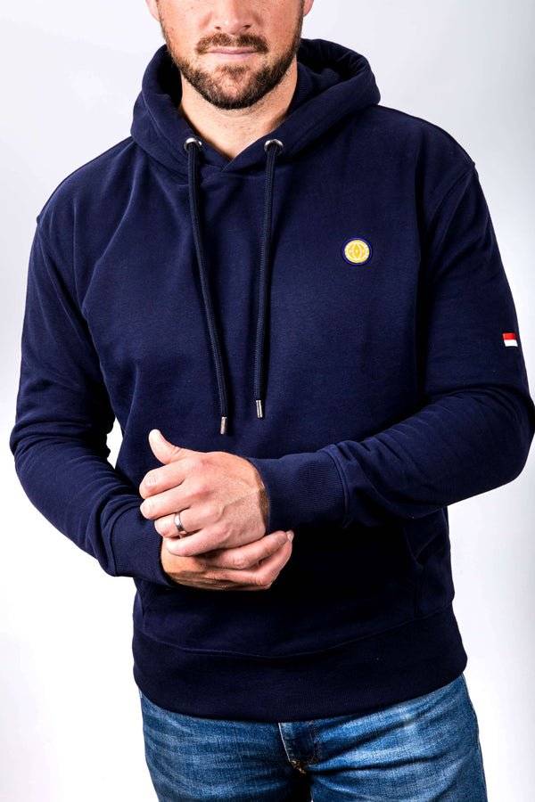 Person wearing a navy blue hoodie with a small logo on a white background