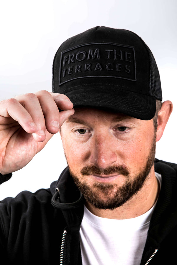Man wearing a black cap with 'From the Terraces' text on a white background
