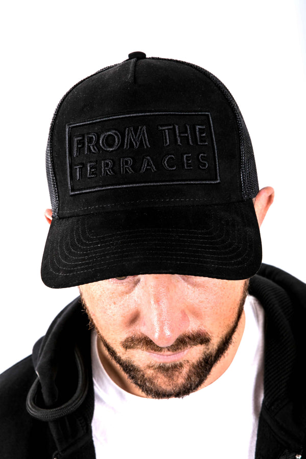 Black cap with 'From the Terraces' text worn by a person on a white background