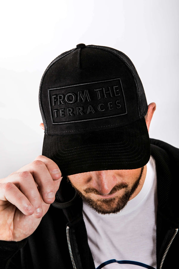 Person wearing a black cap with 'From the Terraces' logo on a white background