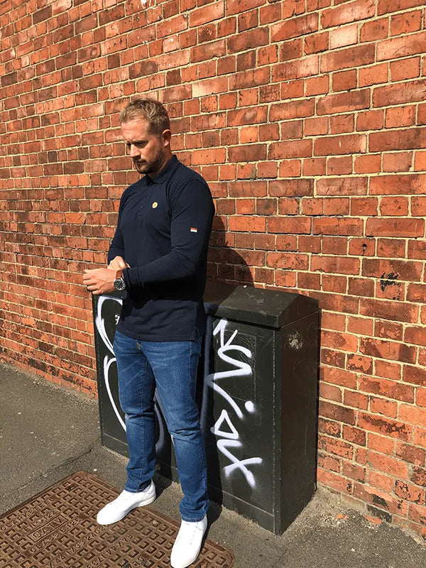 Man leaning against a brick wall with graffiti on a black box