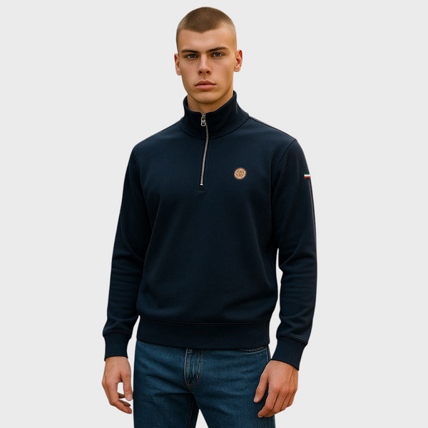 Man wearing a dark blue quarter-zip sweater with a logo on a light gray background