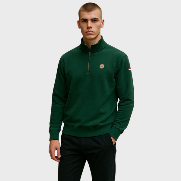 Man wearing a green quarter-zip sweatshirt with a logo on a light gray background