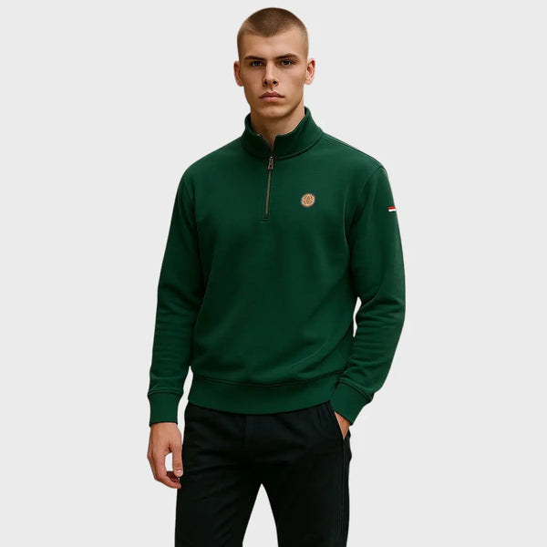 Man wearing a green quarter-zip sweatshirt with a logo on a light gray background