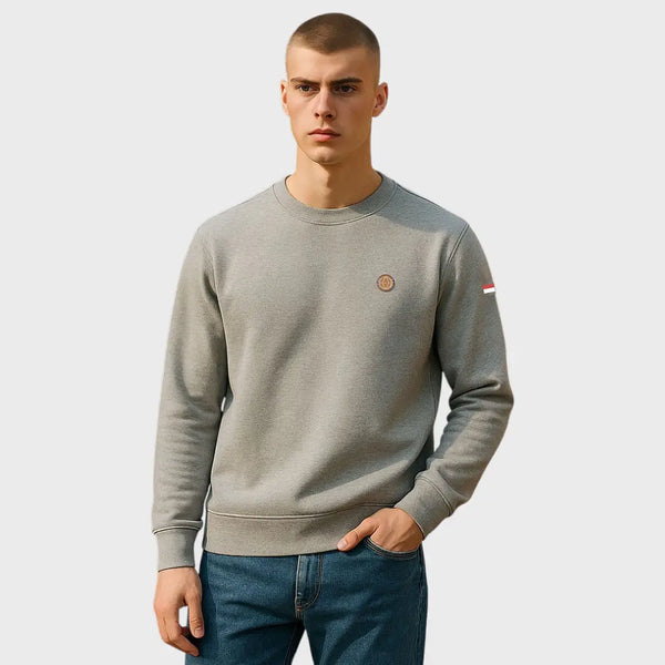 Man wearing a gray sweatshirt with a small logo on a light gray background