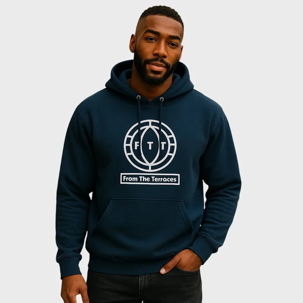 Man wearing a navy hoodie with 'From The Terraces' logo on a light gray background