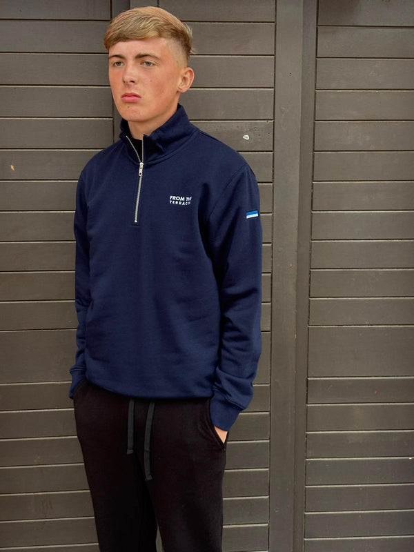 Person wearing a navy blue sweatshirt with a logo against a gray wooden background