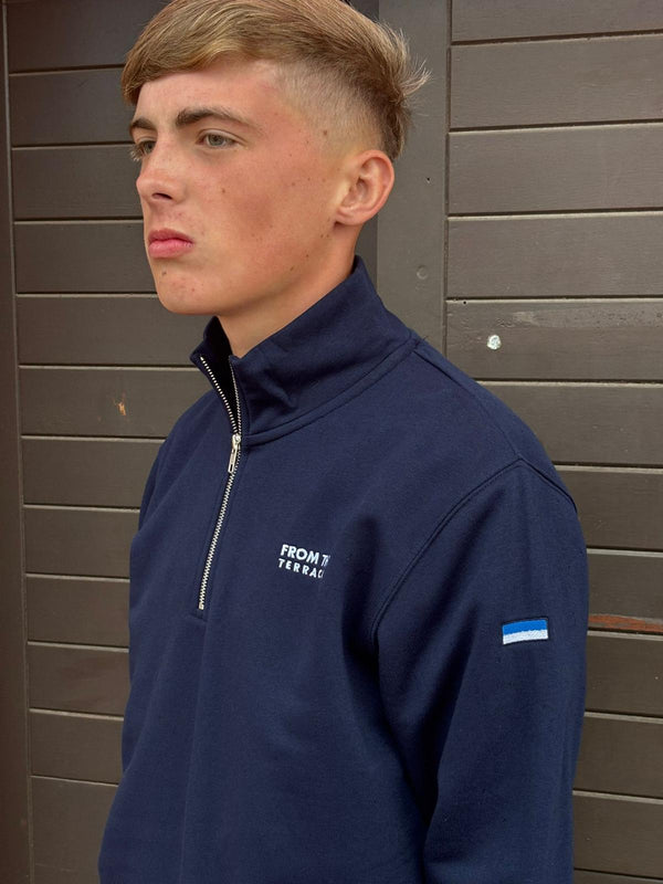 Person wearing a navy blue jacket with a brand logo against a wooden background