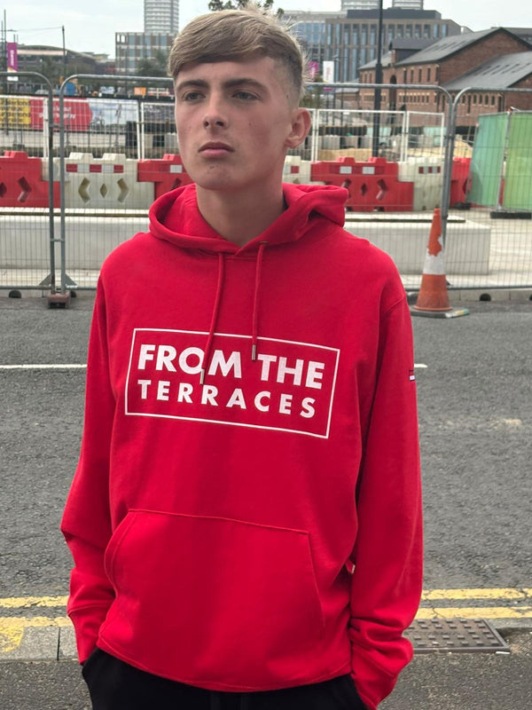 Person wearing a red hoodie with 'From the Terraces' text in an urban setting
