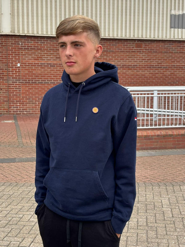 Person wearing a navy hoodie with a small yellow logo, standing outdoors.