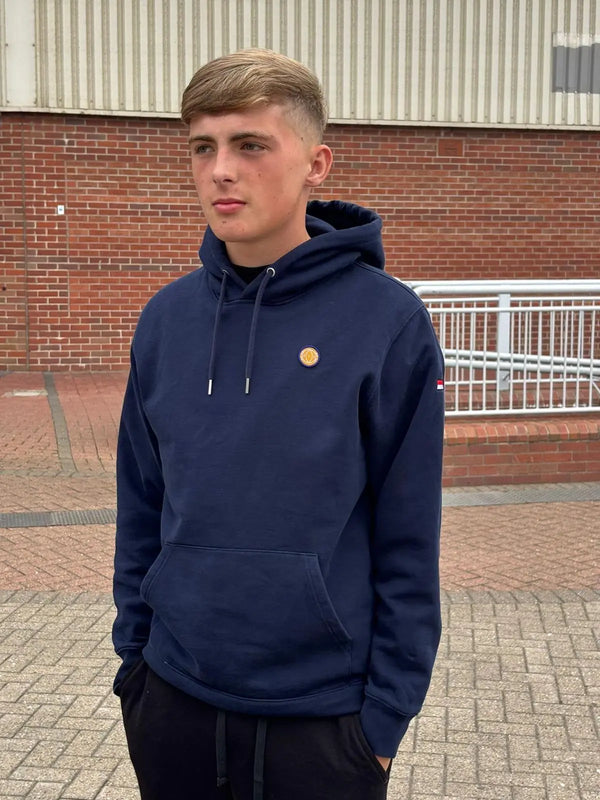 Person wearing a navy hoodie with a small yellow logo, standing outdoors.