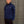 Person wearing a navy blue sweatshirt with a logo against a gray wooden background