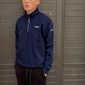 Person wearing a navy blue sweatshirt with a logo against a gray wooden background