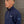 Person wearing a navy blue jacket with a brand logo against a wooden background