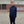 Man wearing a navy blue jacket with a logo on a paved area.