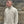 Person wearing a beige pullover with a logo against a stone wall