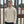 Person wearing a beige pullover with a logo, standing in front of a metal gate.