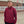 Person wearing a maroon pullover with a small logo, standing outdoors.