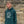 Person wearing a green hoodie with a logo against a stone wall